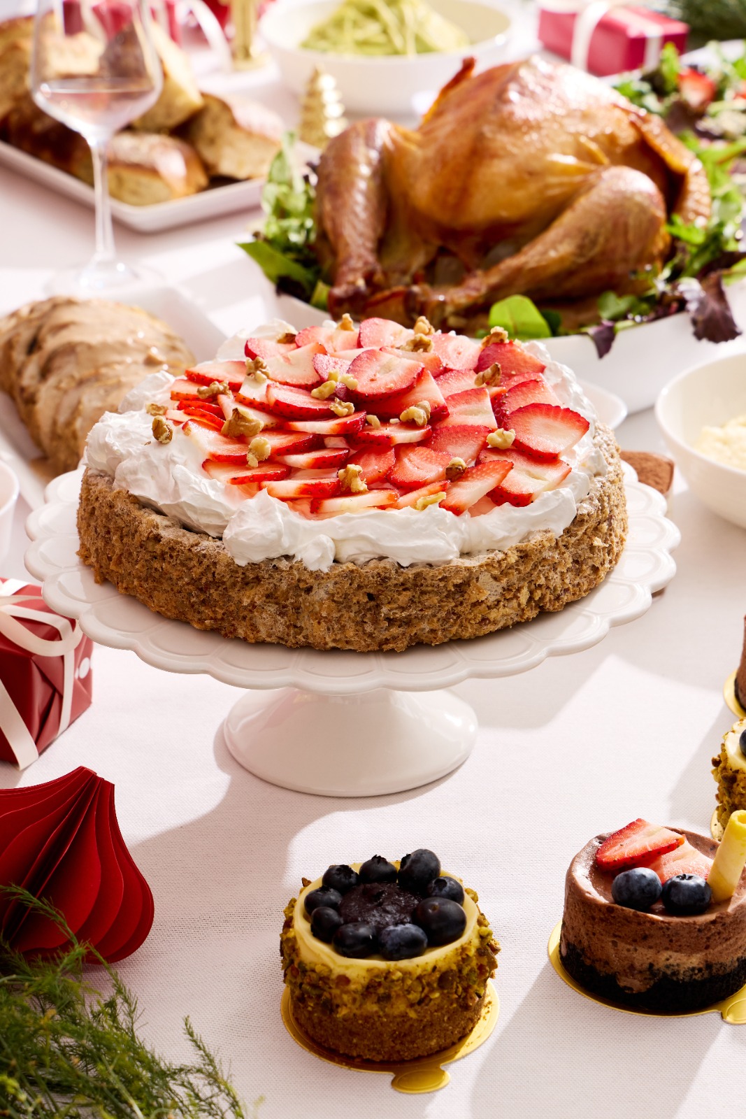 Pastel de fresas, postres individuales y complementos en la mesa navideña
